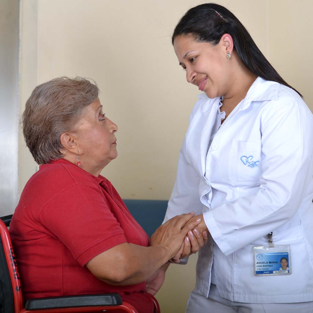 Enfermera sosteniendo la mano de una paciente mientras la atiende con empatía